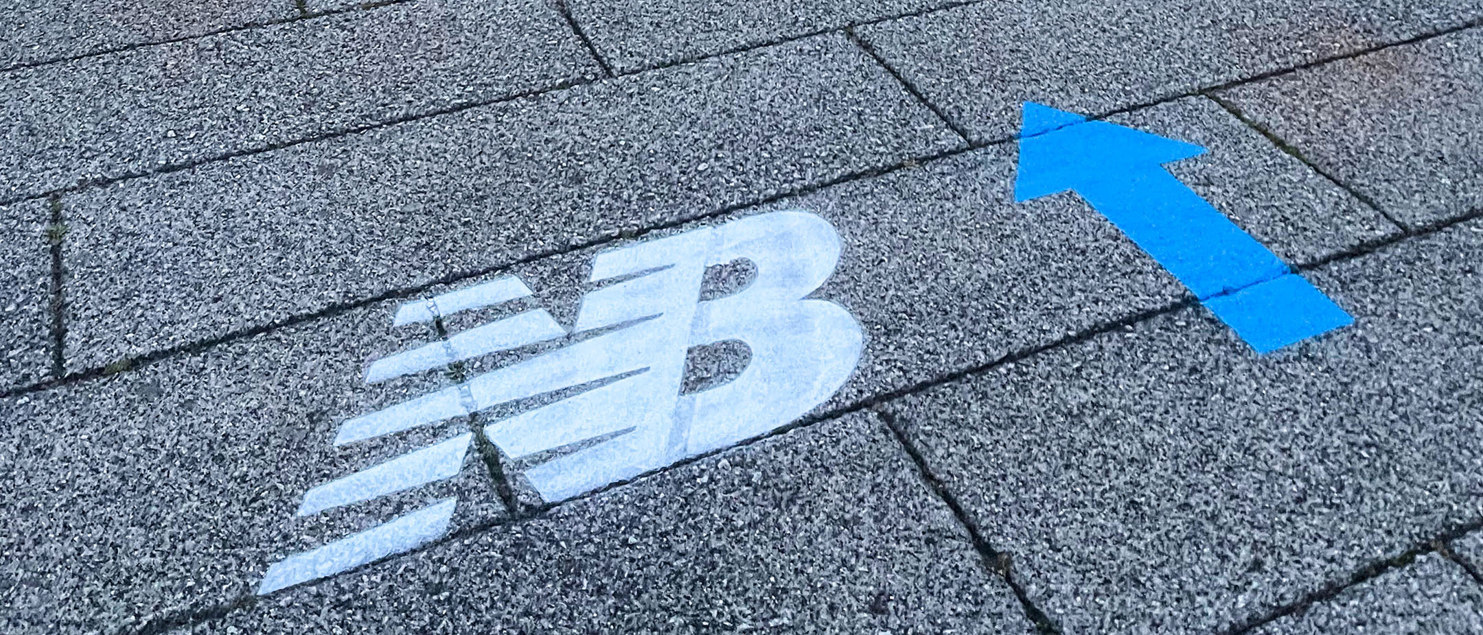 New Balance logo and blue arrow clean graffitied onto the pavement